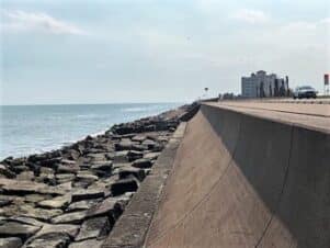 To the left is the Gulf, then a flat area of rocks where you could stand (to fish, or daydream) then the right side of the picture shows the wall, with the sidewalk on top, going out to the horizon. There, the pathway ends, and changes to drivable beach. (But that's not in the photo)