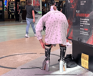 The scantily-clad Fremont Street Performer adjusts his boots before dis-robing.