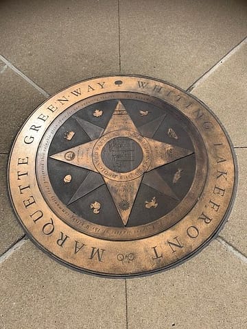 A big round brass marker, identifying the Marquette Greenway