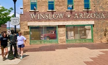 interesting attractions on Route 66 in Arizona: The city of Winslow. In this photo, Two adult women standing on the corner with a statue-man.
