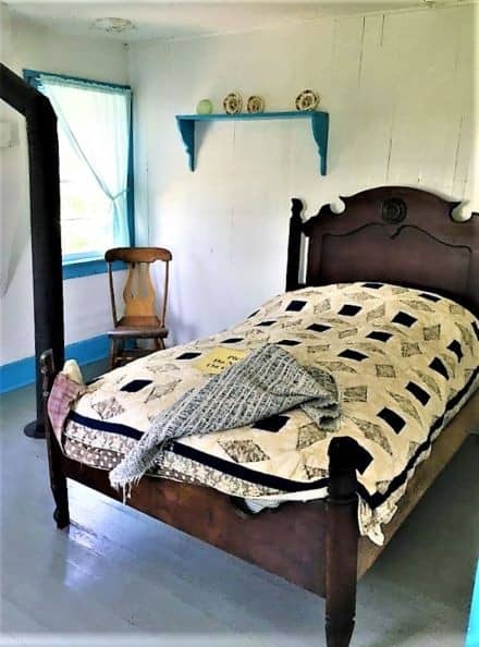 A bed with a headboard, footboard, and checkered quilt.