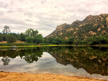 A mountain and its reflection at the edge of a small placid lake.