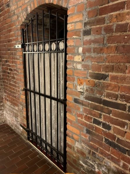 A brick wall and an iron gate (a jail cell).