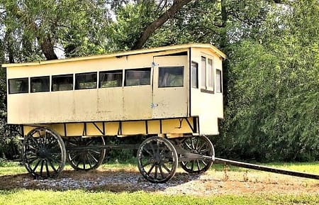 A long covered wagon serves as a school bus