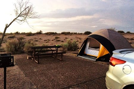 The tail end of a Ford Focus is visible on the right of the picture. Then you see the tent near a picnic table. Behind that is the expansive desert of norther Arizona.