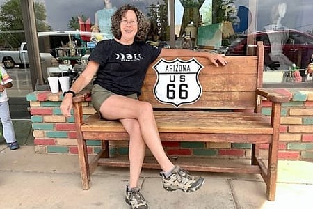 A woman sitting on a bench with a Route 66 sign on it.