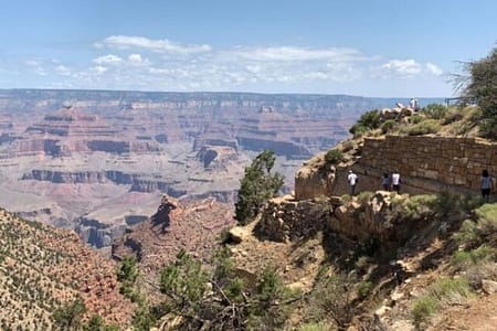 A picture of the Grand Canyon, with several people walking on a narrow trail, as it descends into the Grand Canyon.