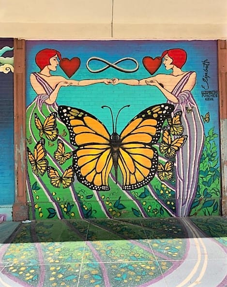 One of the colorful murals on the streets of Galveston. This one has an infinity sign between two people who each have an arm reaching out to the other and HEARTS nearby. A big butterfly separates them.