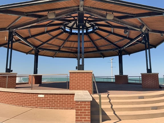 This gazebo has a round base with 5 steps leading up to a platform, which is covered by a round roof (with no walls). It is located at one end of the park, and offers a nice view of Chicago and Lake Michigan
