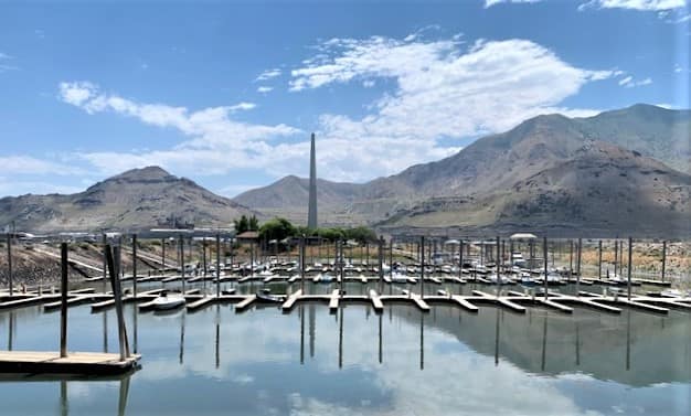 The marina at the State Park in Salt Lake City shows most of the slips empty. Low mountains in the background, with an obelisk towering above the horizon.