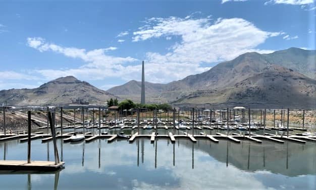 The marina at the State Park in Salt Lake City shows most of the slips empty. Low mountains in the background, with an obelisk towering above the horizon.