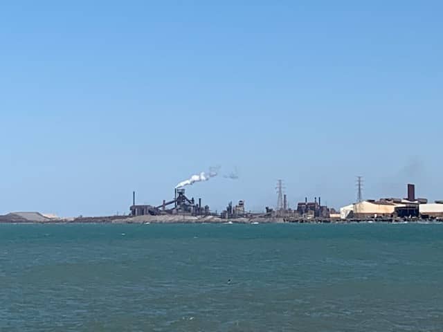 On the horizon we see factories belching smoke into the environment.