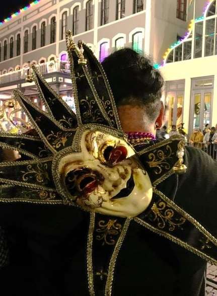 A Mardi Gras mask hanging on somebody's back.