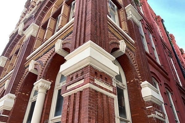 Smooth red bricks tower high on this brick building downtown. Smooth white trim on the windows and doors break-up the redness of the bricks.