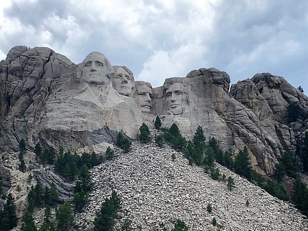 Four Presidential Faces engraved into/out of the rocky mountainside; the National Monument they call Mount Rushmore: George Washington, Thomas Jefferson, Theodore Roosevelt, and Abraham Lincoln..