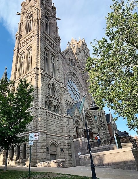 This might be a church. A tall tower on the left seems to match the tall tower on the right, except for perspective. (The one on the right seems shorter, because the camera is closer to the one on the left). Between them is the middle section, which has a stairway leading to a doorway. Arched windows and doorways make this building look ornate.