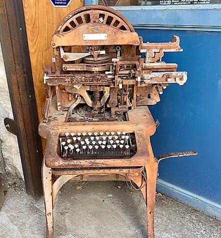 A very old machine that looks like it could be a printing press, but it looks similar to a typewriter.