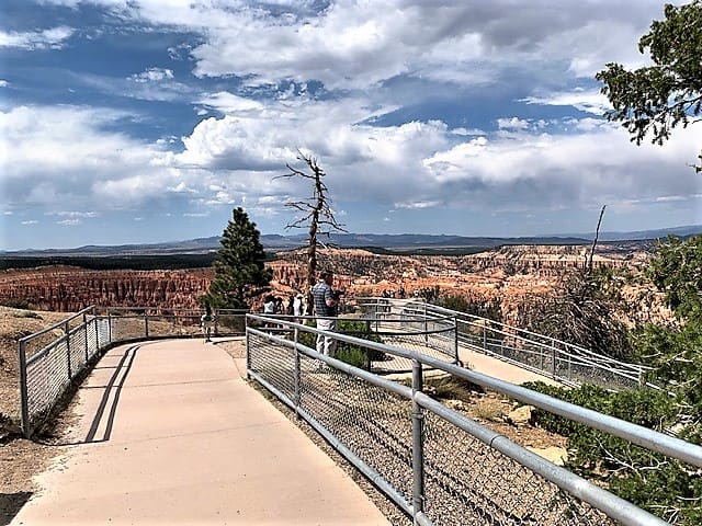 A paved walkway, fenced on either side, stretches out into Bryce Canyon for a view.