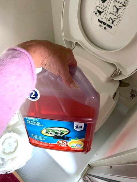 A picture of a jug with orange fluid in it, and the open toilet bowl partially obscured in the background.